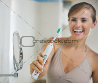 Closeup on electric toothbrush in hand of smiling young woman