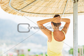 Young woman under umbrella looking into distance . rear view
