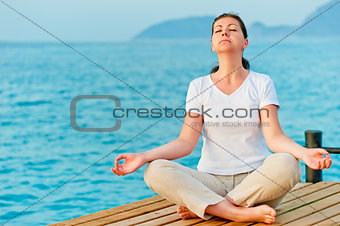 girl sitting on a pier in the lotus position