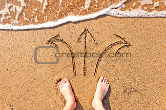 men's bare feet in the sand and arrows