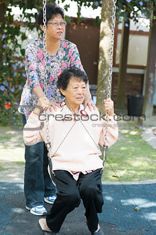 Asian senior women playing swing at outdoor garden park