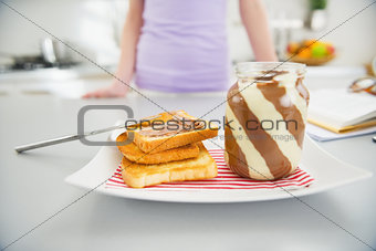 Closeup on toast with chocolate cream and girl in background