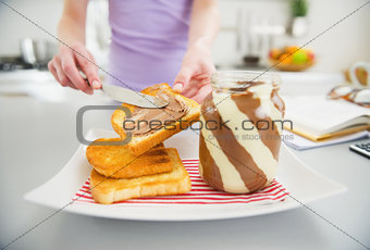 Closeup on young woman making toast with chocolate cream