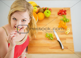 Portrait of happy young woman having a bite while cutting salad