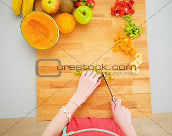 Portrait of young housewife making fruits salad