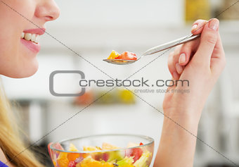 Closeup on happy young woman eating fruits salad