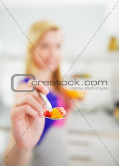 Closeup on young woman stretching spoon with salad in camera