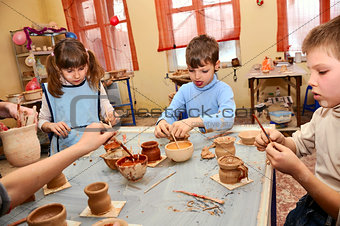 group of children decorating their clay pottery