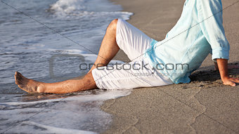 Man sitting on beach in the sunrise light.