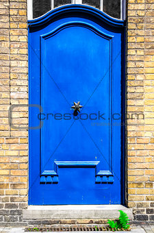 Blue entrance door in brick wall