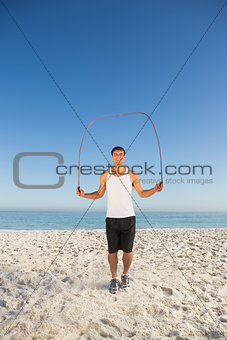 Smiling sporty man jumping rope