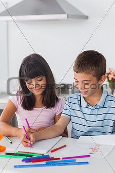 Happy siblings drawing in kitchen
