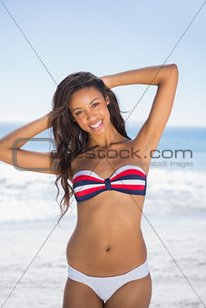 Smiling sexy tanned brunette posing with hands up