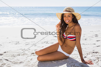 Smiling young tanned woman wearing straw hat posing