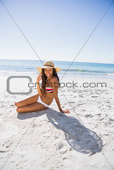 Happy young tanned woman wearing straw hat posing