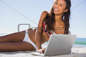 Happy attractive young woman in bikini with her laptop