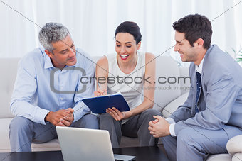 Woman signing contract as husband and salesman watch