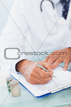 Hand of a doctor writing on a prescription pad