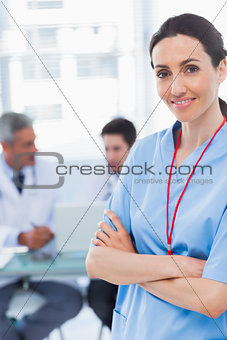 Nurse crossing arms with her colleagues behind