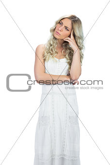 Thoughtful attractive model in white dress posing touching her head