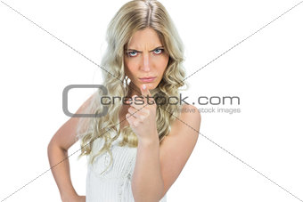 Frowning seductive model in white dress pointing at camera