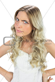 Angry blond model in white dress frowning at camera