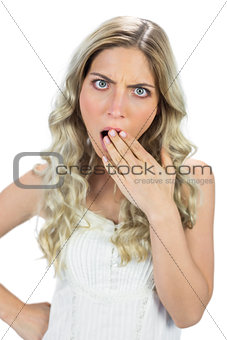 Shocked blond model hiding her mouth wide open