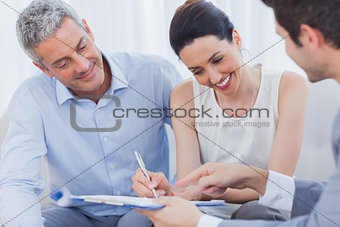 Smiling woman sign on a contrat with her partnership on sofa
