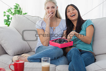 Friends laughing and sharing box of chocolates
