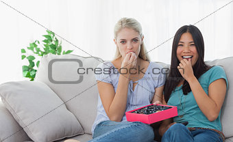 Friends smiling and sharing box of chocolates