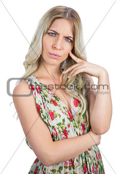 Frowning pretty blonde wearing flowered dress posing