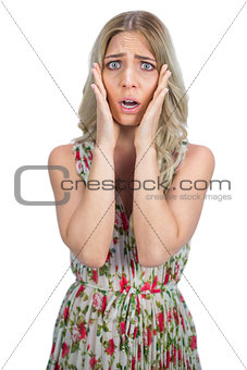 Unhappy blonde wearing flowered dress posing
