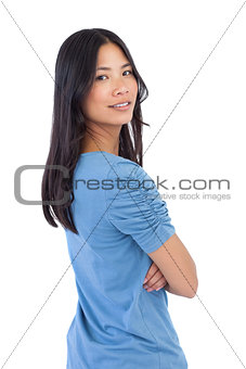 Smiling asian woman with arms crossed looking over her shoulder