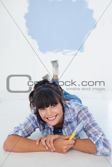 Attractive woman lying on floor holding paint brush