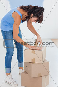 Brunette taping up moving boxes