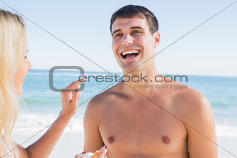 Woman putting sun cream on boyfriends nose