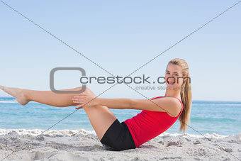 Fit blonde doing pilates core exercise smiling at camera