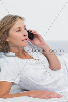 Blonde woman lying on bed making a phone call