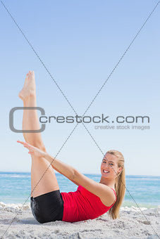 Athletic blonde doing pilates core exercise smiling at camera