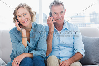 Cheerful couple on their mobile phones on the couch
