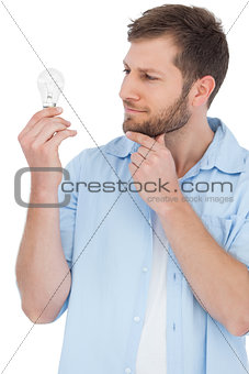 Sceptical model holding a bulb and touching his chin