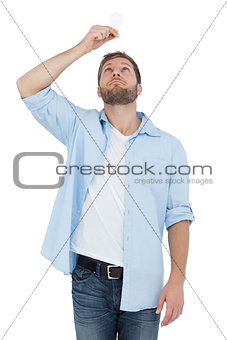 Sceptical model holding a bulb above his head