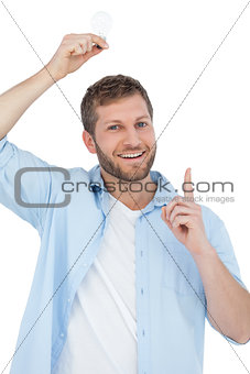 Smiling model holding a bulb above his head