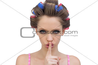 Model in hair rollers posing with finger on mouth
