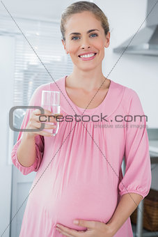 Cheerful expecting woman drinking water