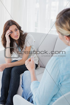 Upset woman sitting with her therapist talking to her