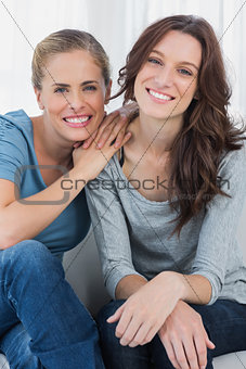 Delightful friends posing while sitting on the couch