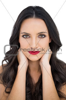 Dark haired woman with red lips touching her neck