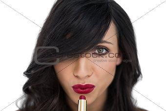 Sexy brunette applying red lipstick
