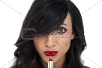 Sexy brunette applying red lipstick on her mouth